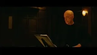 Elderly bald man with music stand in dimly lit room — Whiplash