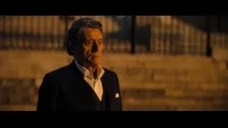 Elderly man in suit standing by brick wall — John Wick: Chapter 4
