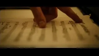Hand pointing at sheet music on desk — Whiplash