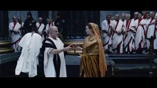 Man and woman on stage with robed people — Gladiator