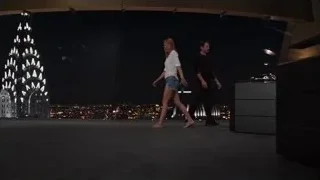 Man and woman walking on stage with city skyline — The Avengers