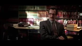 Man in suit sitting before bookshelf — Batman: The Dark Knight