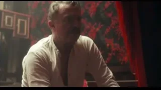man sitting in dimly lit room with red curtain — Peaky Blinders