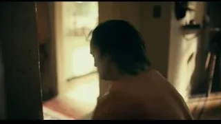 Shirtless man on bed looking out window — Joker