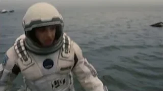 woman in space suit standing by water — Interstellar