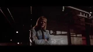 Woman standing in dimly lit industrial room — American Psycho